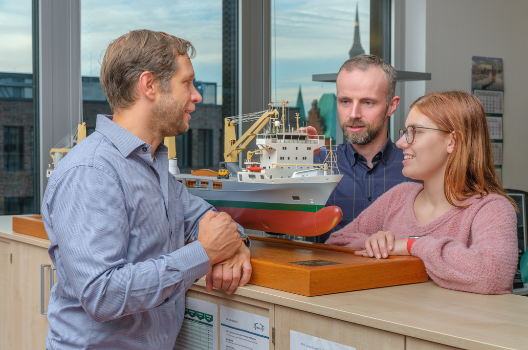 Employees in front of a ships model